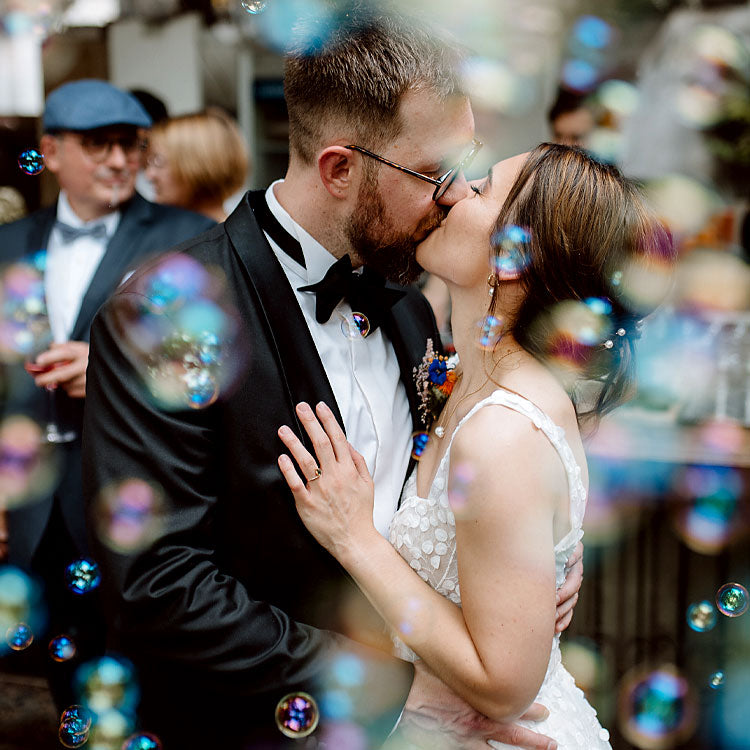 Brautpaar küsst sich auf der Hochzeitsfeier, romantische Szene mit Seifenblasen im festlichen Ambiente