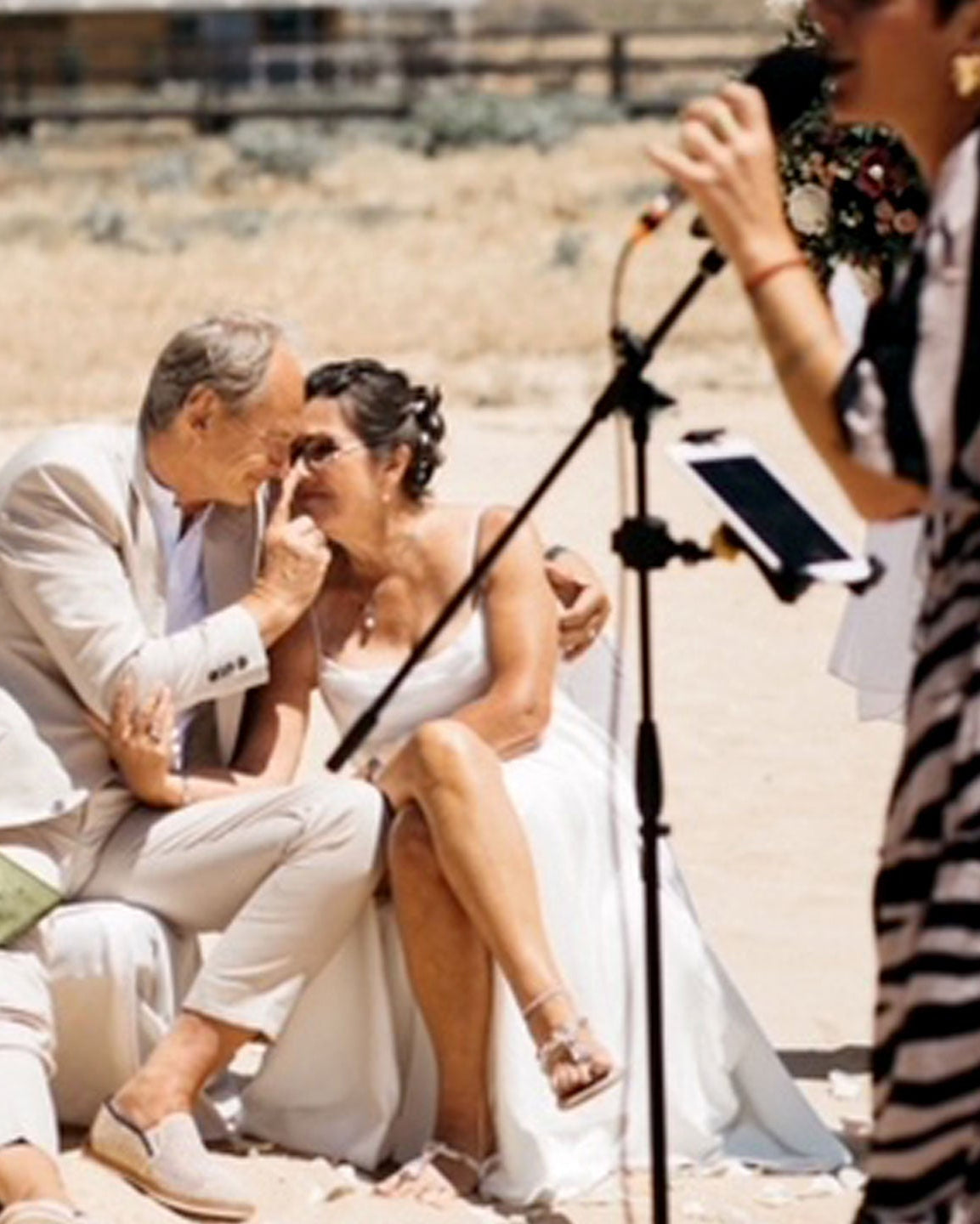 Goldene Hochzeit am Strand in Portugal, Brautpaar sitzt innig zusammen während die freie Rednerin die Zeremonie hält