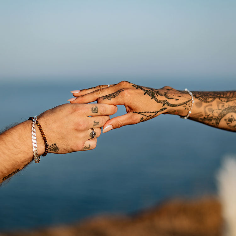 Detailaufnahme von Braut und Bräutigam, die sich bei freier Trauung in der Algarve die Hände reichen mit Tattoos und Ringen
