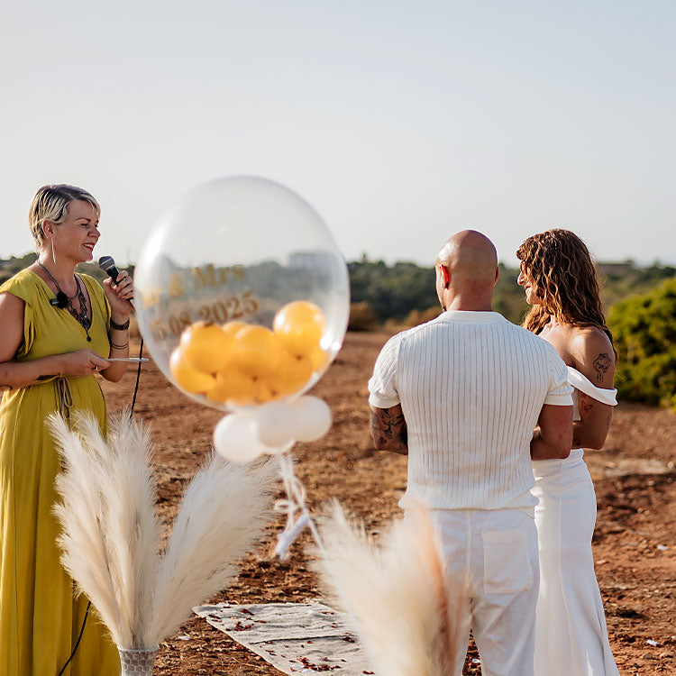 Freie Traurednerin gestaltet eine Hochzeit im Freien an der Algarve, Brautpaar steht vor ihr in Boho-Deko