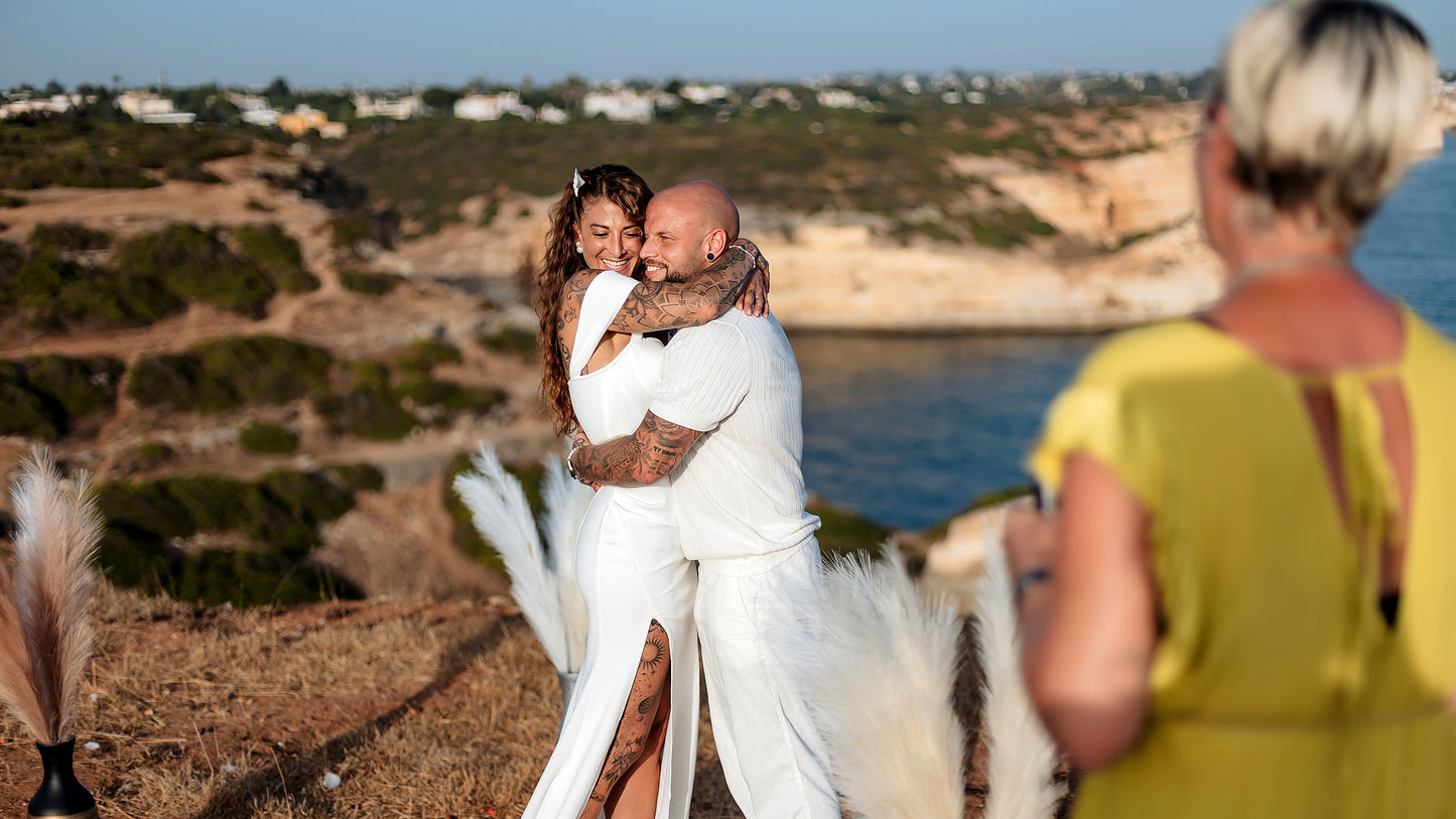 Brautpaar umarmt sich glücklich bei freier Trauung auf den Klippen der Algarve mit Meerblick
