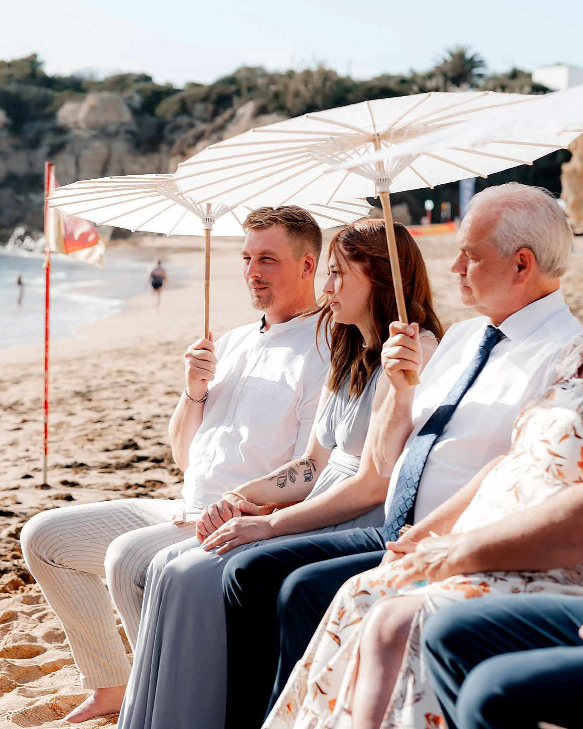 Freie Trauung am Strand mit Gästen die Sonnenschirme in den Händen halten aus Reispapier