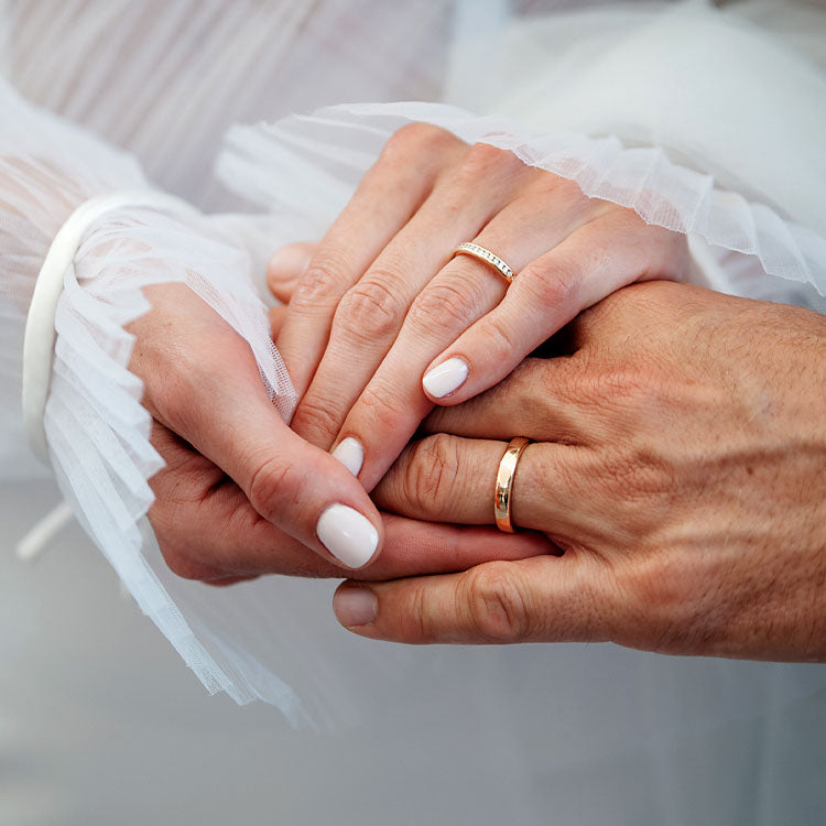 Detailaufnahme von Braut- und Bräutigamhänden mit Eheringen, Symbol für den Ringtausch bei der Hochzeit