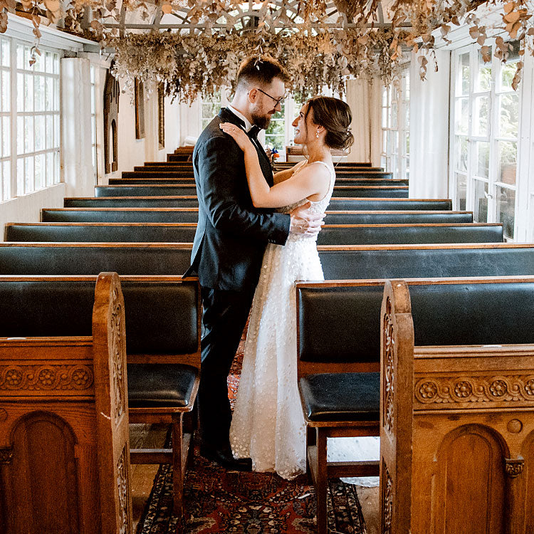 Brautpaar umarmt sich verliebt in einer festlich geschmückten Kapelle mit Kerzen und Blumen